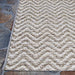 Couristan Cape Indoor/Outdoor Rug - Marion/Light Brown-Ivory is shown on a stone floor with a neat border and repeating chevron design