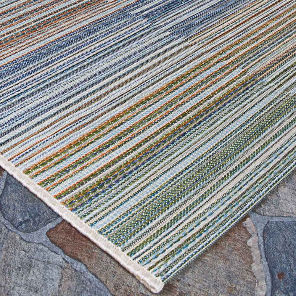 Couristan Cape Indoor/Outdoor Rug - Shoreham/Ivory-Multi is pictured on a stone patio, showing its tightly woven texture and soft edge binding