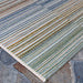 Couristan Cape Indoor/Outdoor Rug - Shoreham/Ivory-Multi is pictured on a stone patio, showing its tightly woven texture and soft edge binding