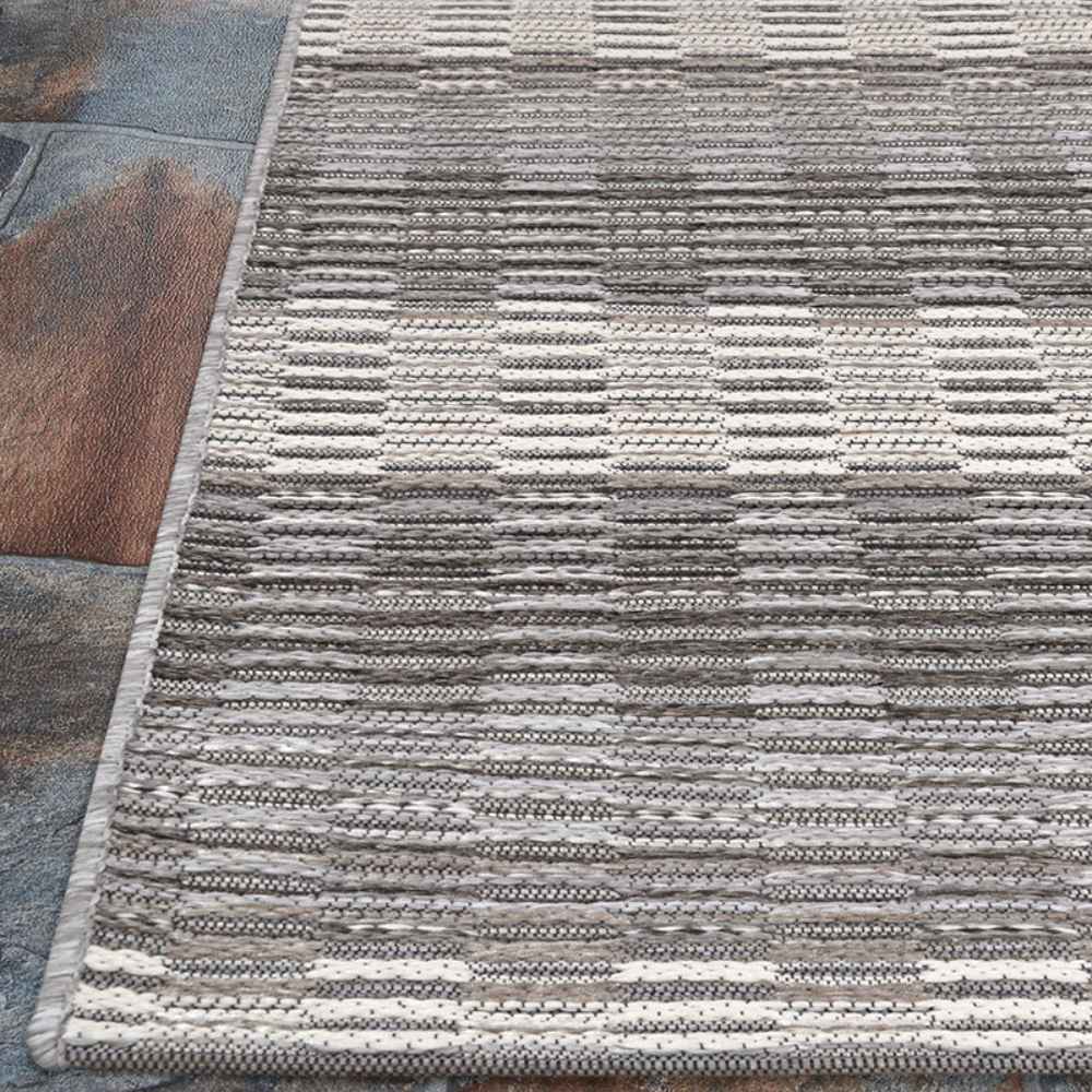 Couristan Cape Indoor/Outdoor Rug - Torrent/Sky Blue-Grey rests partially over a rustic tile floor