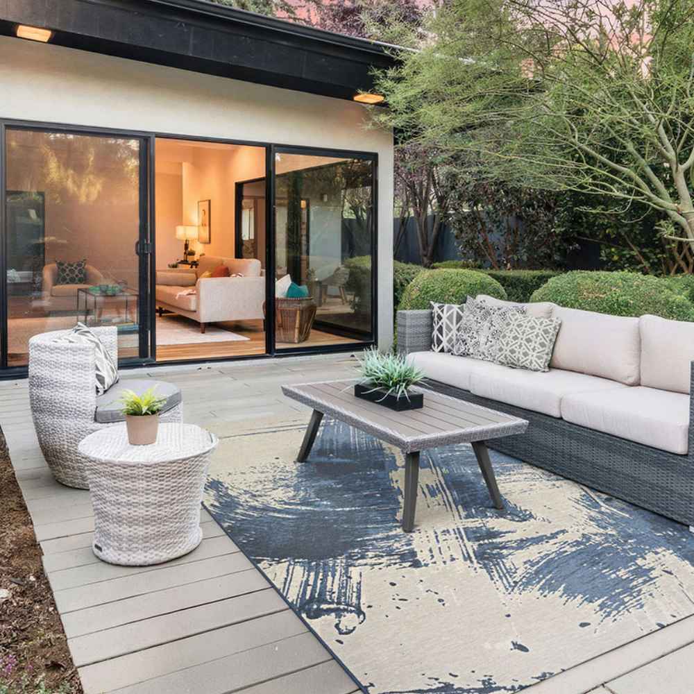 Couristan Castille Indoor/Outdoor Rug - Canvas/Orion adds style under a coffee table in a sleek outdoor patio setup next to a sliding glass door