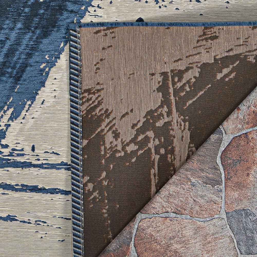 Couristan Castille Indoor/Outdoor Rug - Canvas/Orion is shown flipped to reveal its front and back sides, along with the stone floor beneath it