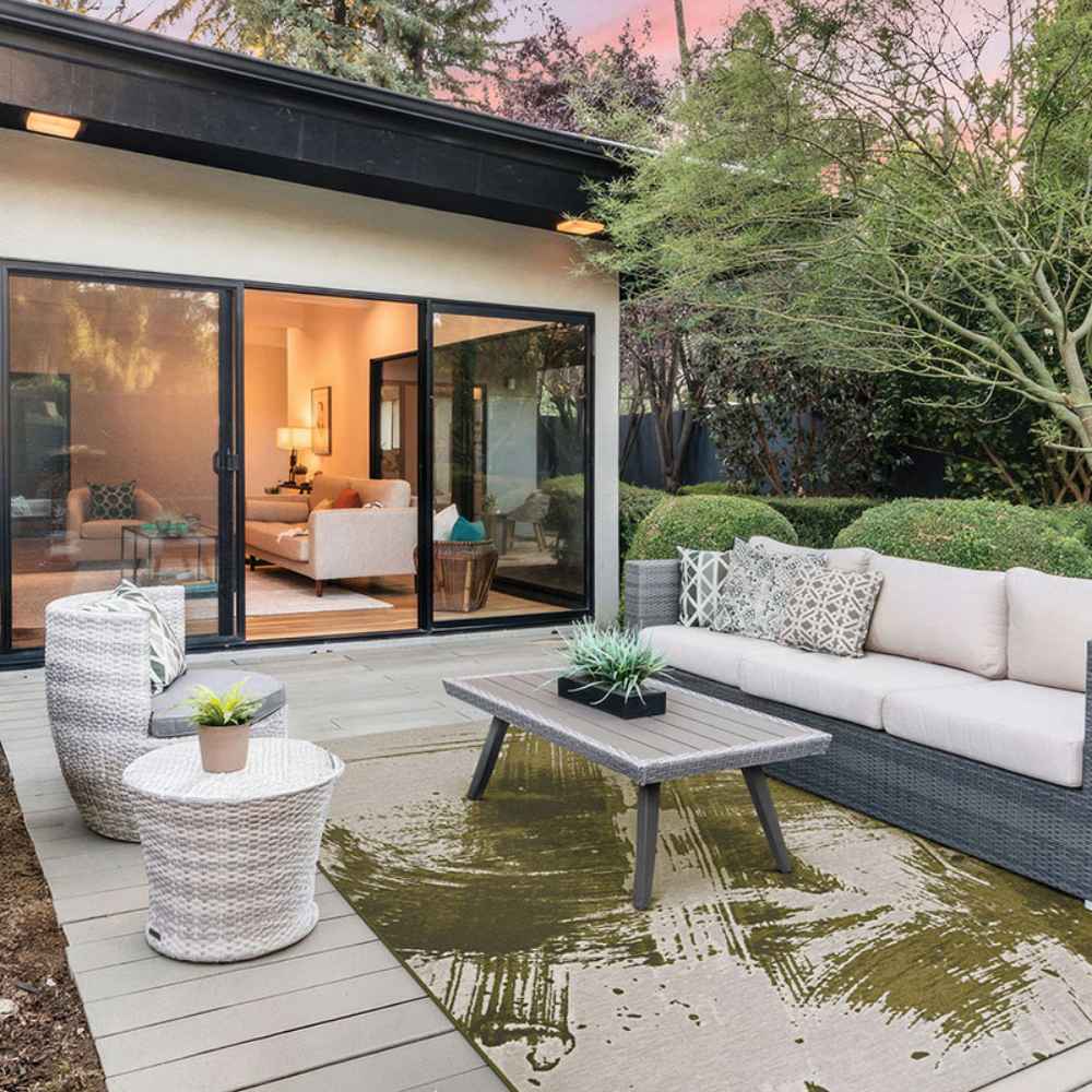 Couristan Castille Indoor/Outdoor Rug - Canvas/Tea Leaf lies stylishly under a patio seating set