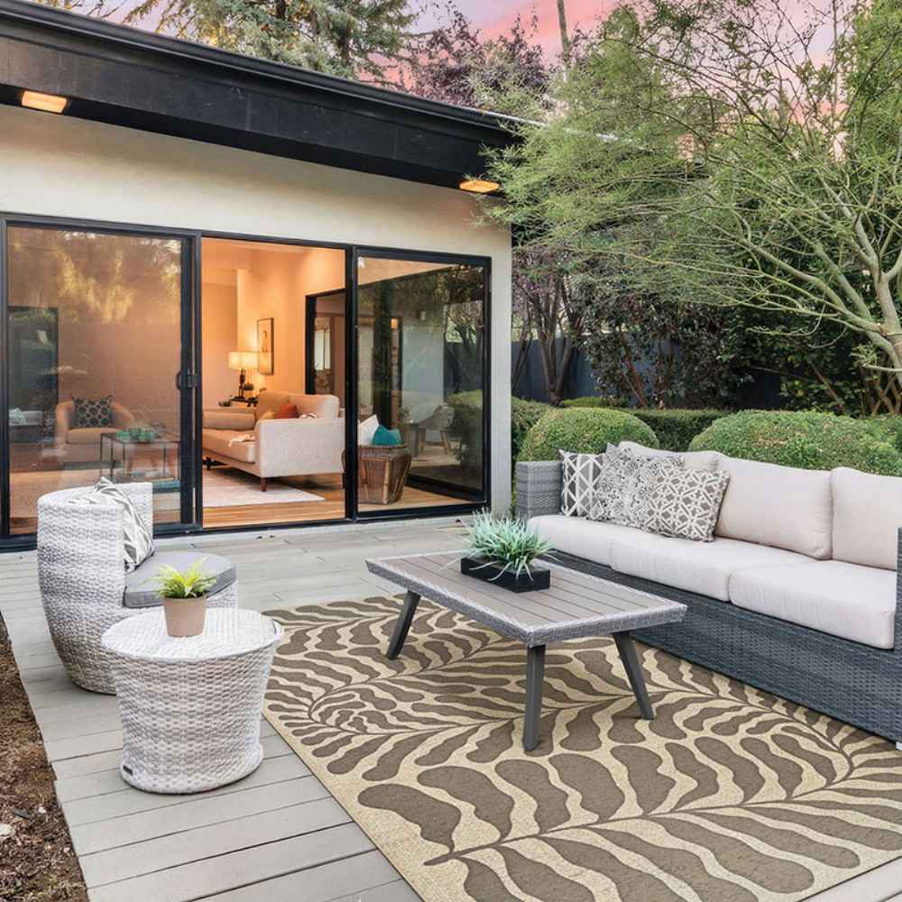 Couristan Castille Indoor/Outdoor Rug - Fiore/Mocha lies under a modern outdoor seating set