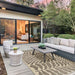 Couristan Castille Indoor/Outdoor Rug - Fiore/Mocha lies under a modern outdoor seating set