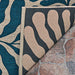 Couristan Castille Indoor/Outdoor Rug - Fiore/Petrol is flipped to show its backing and thick edges, laid over a textured stone floor
