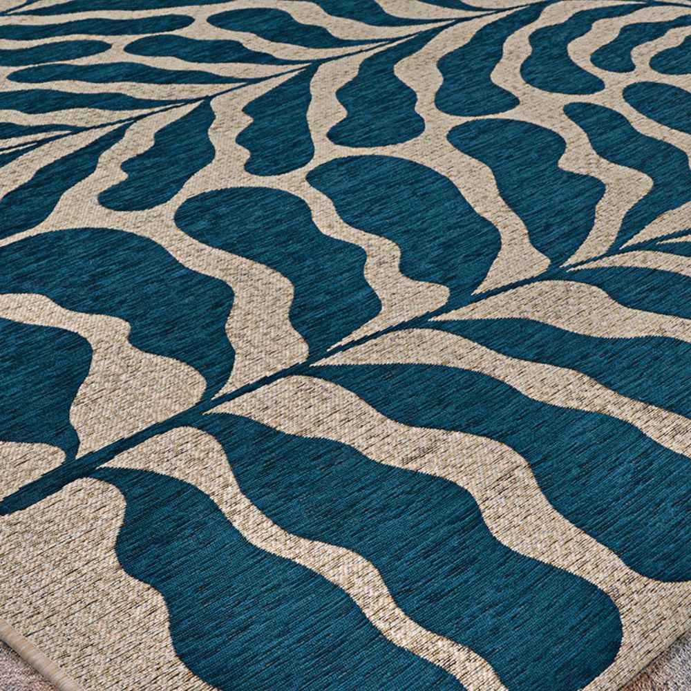 Couristan Castille Indoor/Outdoor Rug - Fiore/Petrol is shown lying flat, displaying its bold curving leaf design from a side angle