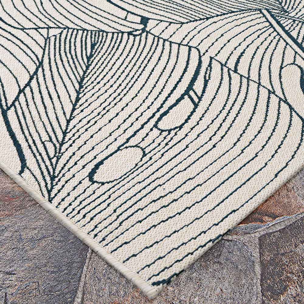 Couristan Castille Indoor/Outdoor Rug - Palma/Petrol corner is displayed on a stone floor
