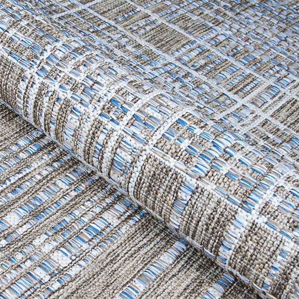 Couristan Charm Indoor/Outdoor Rug - Ohe/Sand-Ivory is partially rolled to reveal its durable weave and layered texture in soft neutral tones