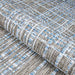 Couristan Charm Indoor/Outdoor Rug - Ohe/Sand-Ivory is partially rolled to reveal its durable weave and layered texture in soft neutral tones