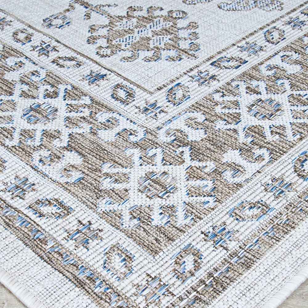 Couristan Charm Indoor/Outdoor Rug - Woodburn/Ivory-Sand is folded to reveal the corner’s layered patterns and contrasting motifs