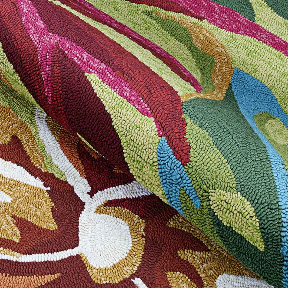 Couristan Covington Indoor/Outdoor Rug - Painted Fern/Fern-Red is partially rolled up, showing its colorful pattern and plush looped construction