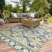 Couristan Covington Indoor/Outdoor Rug - Pegasus/Ivory-Navy-Lime is displayed on a sunny deck with wicker furniture and vibrant greenery