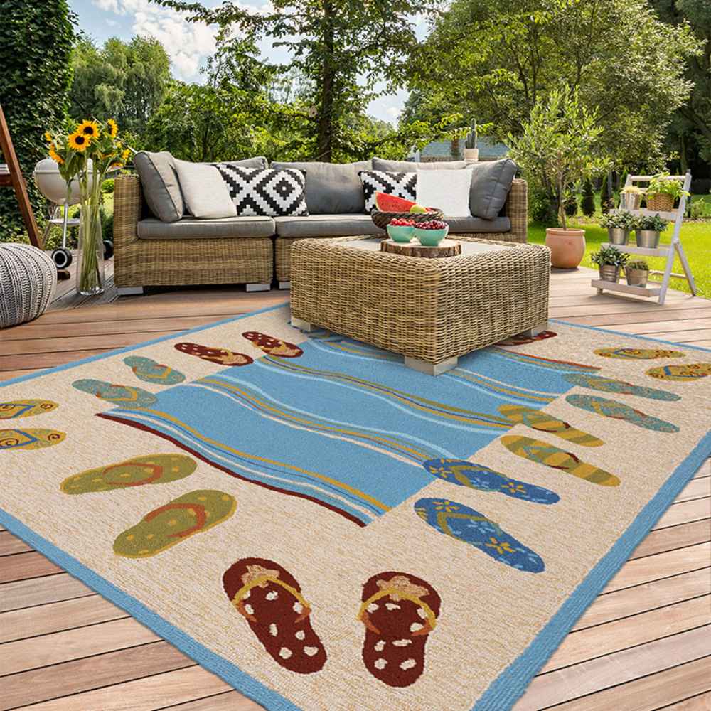 Couristan Covington Indoor/Outdoor Rug - Sandals/Sand-Multi is placed on a patio with wicker furniture