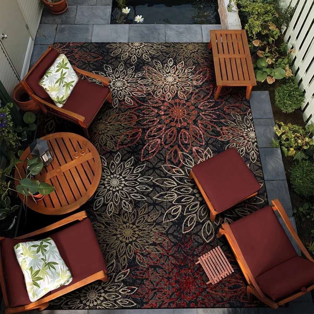 Couristan Dolce Indoor/Outdoor Rug - Amalfi/Multi is beautifully placed on a patio under wooden furniture, creating a cozy and colorful garden setting