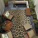 Couristan Dolce Indoor/Outdoor Rug - Amur Leopard/New Gold is displayed in an outdoor patio setup with wooden furniture