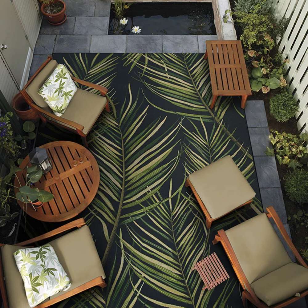 Couristan Dolce Indoor/Outdoor Rug - Bamboo Forest/Cool Onyx decorates an outdoor patio with wooden furniture