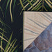 Couristan Dolce Indoor/Outdoor Rug - Bamboo Forest/Cool Onyx is shown from the corner with its underside flipped to reveal the backing and edge stitching