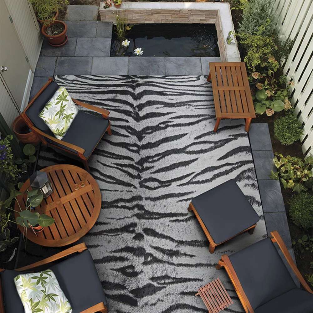 Couristan Dolce Indoor/Outdoor Rug - Bengal/Ivory styled in a cozy outdoor seating area with wooden furniture
