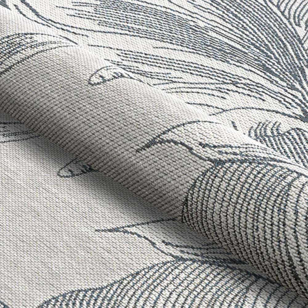 Couristan Dolce Indoor/Outdoor Rug - Flora/Argento is partially rolled to show the flexible, textured weave and dark floral lines