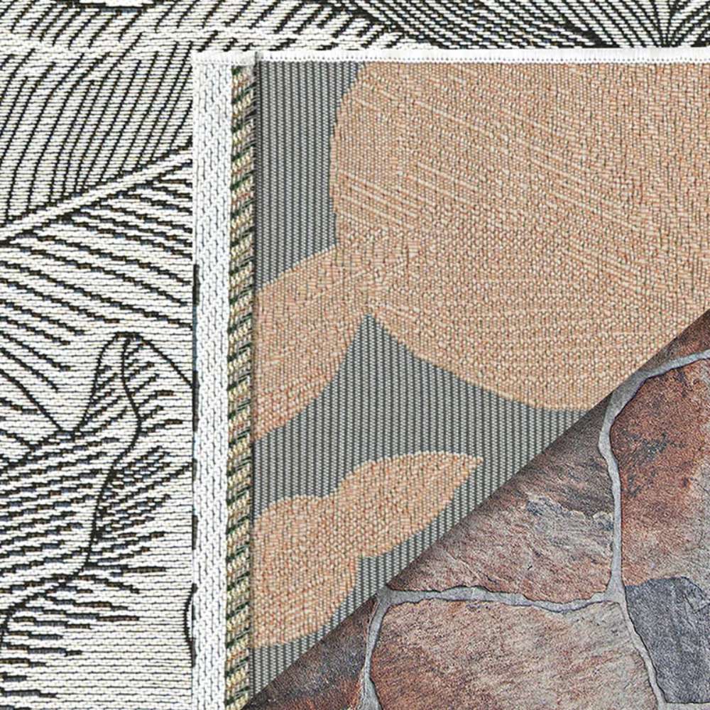 Couristan Dolce Indoor/Outdoor Rug - Flora/Snow is shown with its corner flipped to reveal its backing and intricate two-tone floral weave
