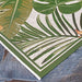 Couristan Dolce Indoor/Outdoor Rug - Flowering Fern/Ivory-Hunter Green shows its crisp corner laid over stone
