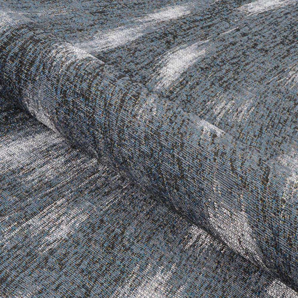 Couristan Dolce Indoor/Outdoor Rug - Hyena/Denim-Silver is partially rolled showcasing its flexibility and thick weave