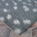 Couristan Dolce Indoor/Outdoor Rug - Hyena/Denim-Silver lies flat on a stone patio with soft ivory patterns on a denim background