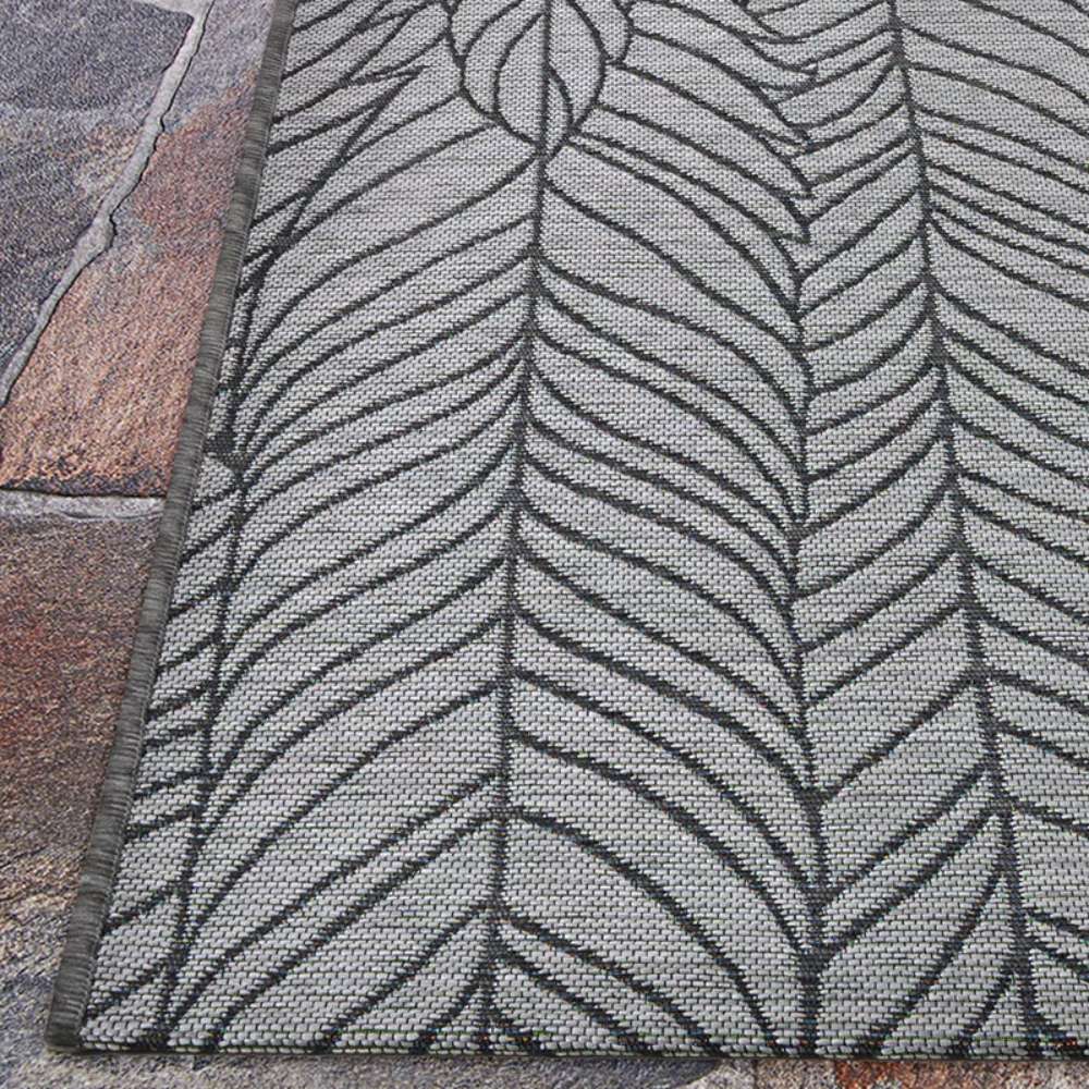 Couristan Dolce Indoor/Outdoor Rug - Majorelle/Silver-Black is laid out fully on a patio