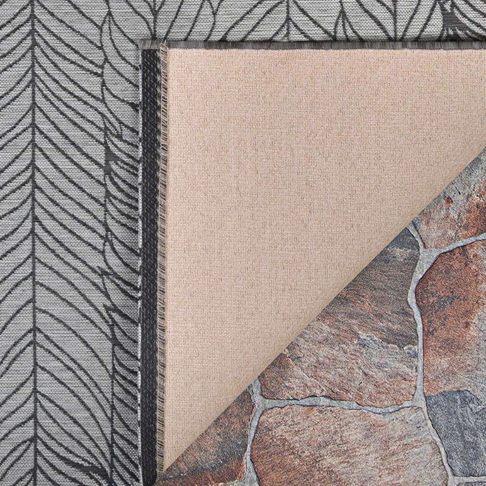 Couristan Dolce Indoor/Outdoor Rug - Majorelle/Silver-Black is shown with a corner flipped over to display its beige backing and durable texture