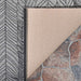 Couristan Dolce Indoor/Outdoor Rug - Majorelle/Silver-Black is shown with a corner flipped over to display its beige backing and durable texture