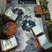 Couristan Dolce Indoor/Outdoor Rug - Novella/Grey is styled on a cozy patio surrounded by wooden furniture and plants
