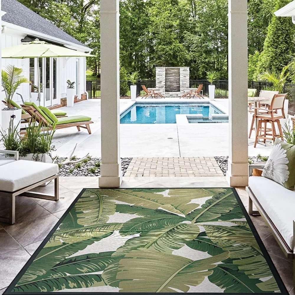 Couristan Dolce Indoor/Outdoor Rug - Palm Lily/Hunter Green-Ivory is placed in a covered patio facing a pool