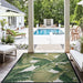 Couristan Dolce Indoor/Outdoor Rug - Palm Lily/Hunter Green-Ivory is placed in a covered patio facing a pool