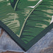 Couristan Dolce Indoor/Outdoor Rug - Palm Lily/Hunter Green-Ivory is shown lying flat on a stone floor with rich green palm leaf patterns and dark green trim