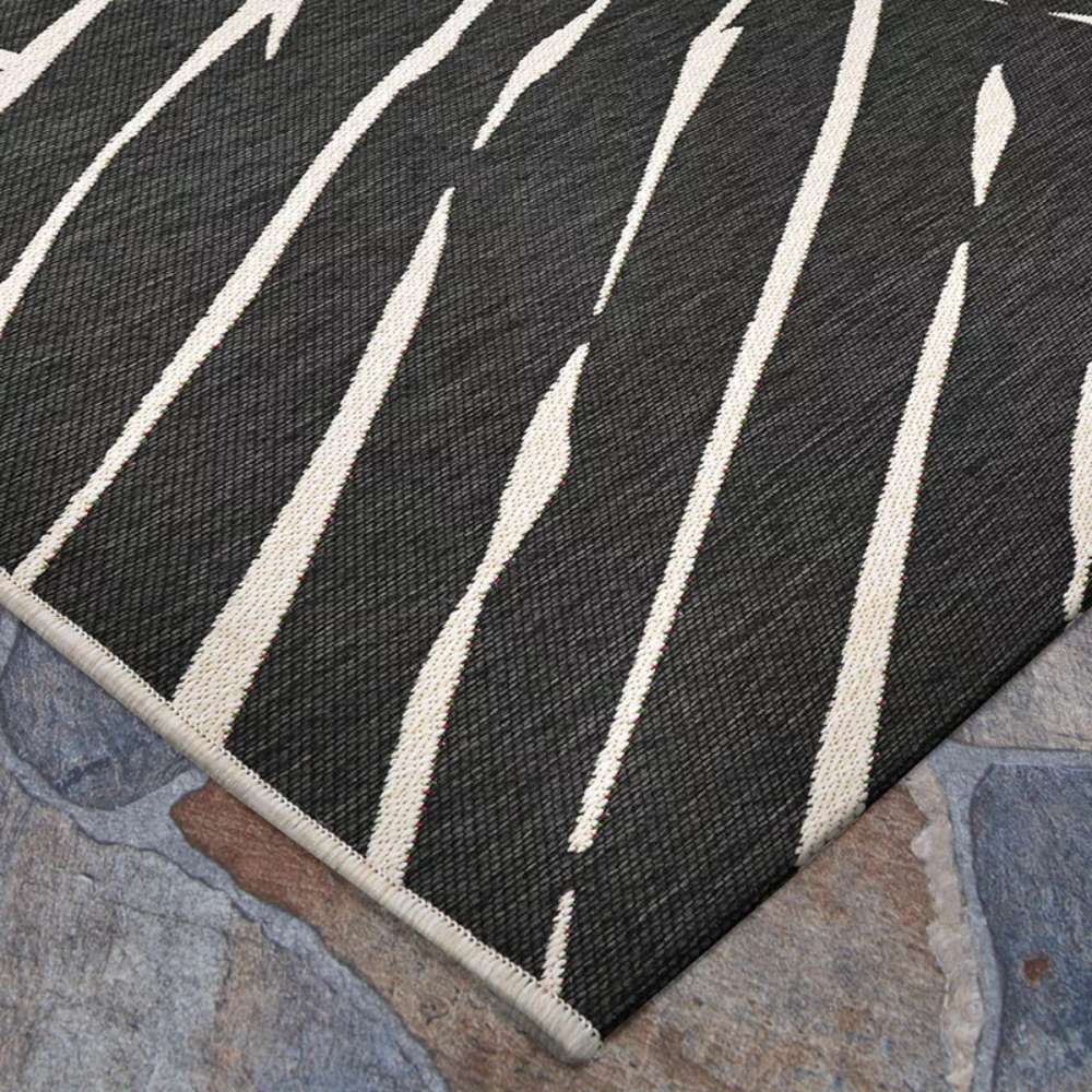 Couristan Dolce Indoor/Outdoor Rug - Parquet/Charcoal lies flat on stone flooring
