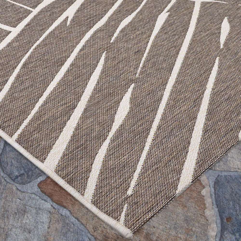 Couristan Dolce Indoor/Outdoor Rug - Parquet/Mocha is shown on a stone patio corner