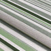 Couristan Dolce Indoor/Outdoor Rug - Striped/Grass is partially rolled to show the textured green and grey striping detail
