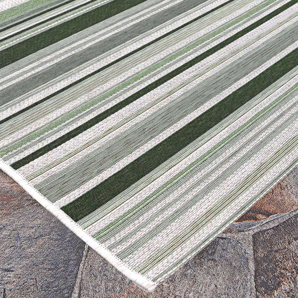 Couristan Dolce Indoor/Outdoor Rug - Striped/Grass is spread over a stone patio