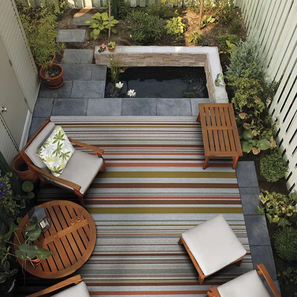 Couristan Dolce Indoor/Outdoor Rug - Striped/Sunset enhances a cozy backyard seating area with warm, multicolored stripes adding a bold focal point