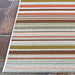 Couristan Dolce Indoor/Outdoor Rug - Striped/Sunset is laid flat on stone pavers