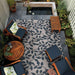 Couristan Dolce Indoor/Outdoor Rug - Summer Ivy/Ivory-Slate Blue is beautifully placed in a cozy outdoor patio surrounded by wooden furniture