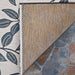 Couristan Dolce Indoor/Outdoor Rug - Summer Ivy/Ivory-Slate Blue is shown from the corner flipped up to reveal its textured brown backing