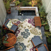 Couristan Dolce Indoor/Outdoor Rug - Tivoli/Ivory-Multi is beautifully laid out in a cozy outdoor patio surrounded by wooden furniture and garden plants