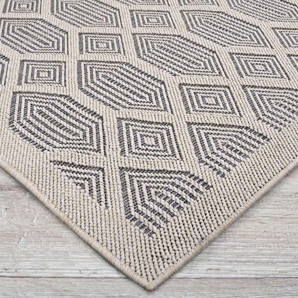 Couristan Liguria Indoor/Outdoor Rug - Rapallo/Pebble is displayed at an angle showing its diamond shapes and tightly bound edges
