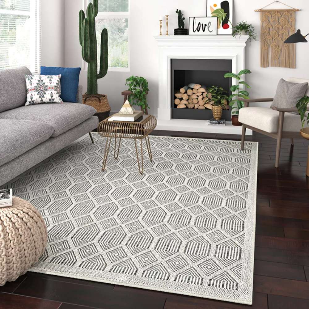 Couristan Liguria Indoor/Outdoor Rug - Rapallo/Pebble is styled in a modern living room with a sofa, plants, and fireplace, blending into the décor