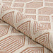 Couristan Liguria Indoor/Outdoor Rug - Rapallo/Umber is partly rolled to highlight its flexibility and detailed woven design