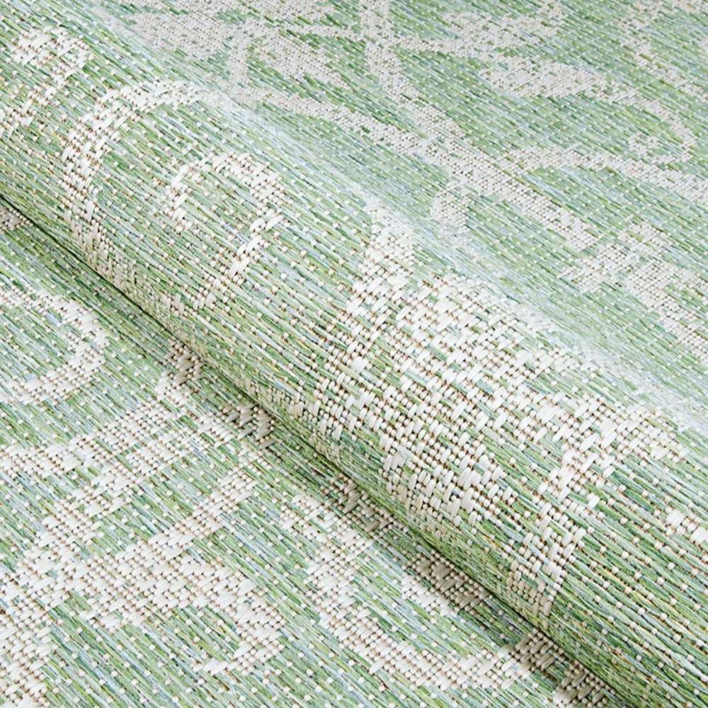 Couristan Monaco Indoor/Outdoor Rug - Summer Quay/Ivory-Light Green is shown partially rolled to reveal its flexible yet durable weave