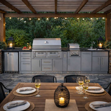 Cozy pergola dining scene with Sunstone Dallas 14ft Outdoor Kitchen Island Package with Gas Hybrid Charcoal Grill, featuring a grill, sink, and warm lighting