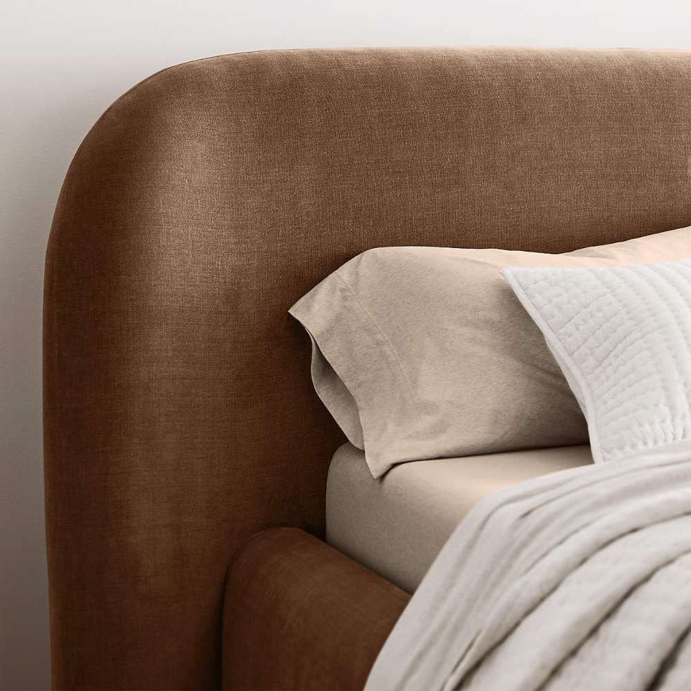 Crate & Barrel Adelaide Curved Upholstered Bed close-up of the curved headboard beside layered pillows and bedding